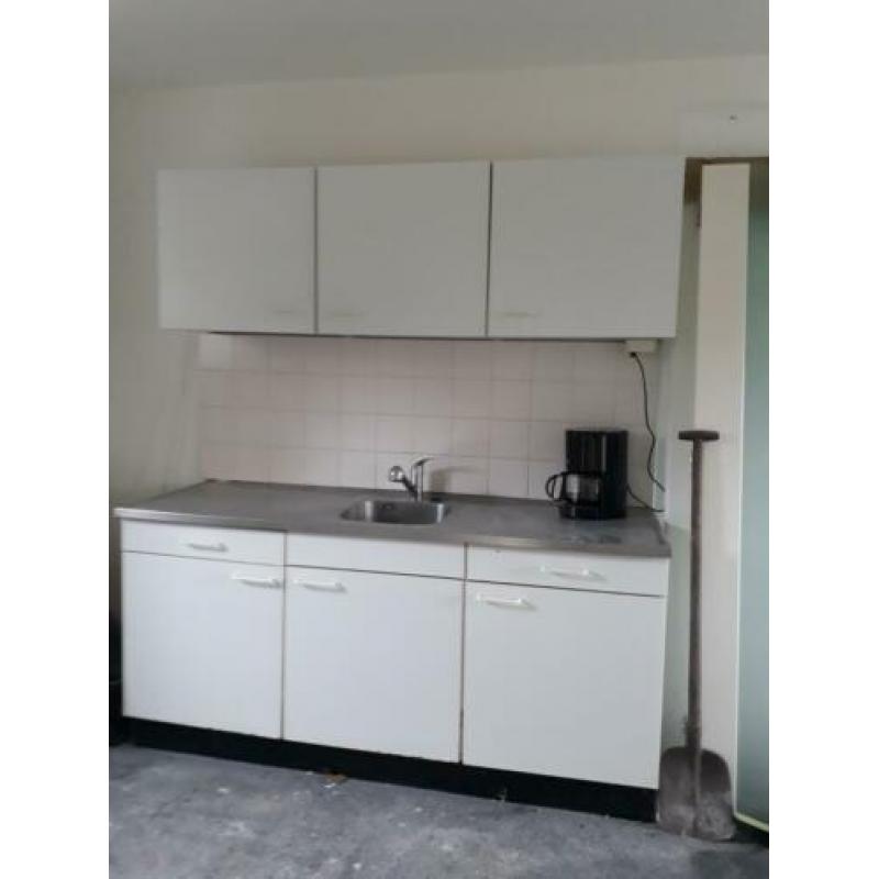 Eenvoudige witte keuken met boiler en uittrekbare kraan.